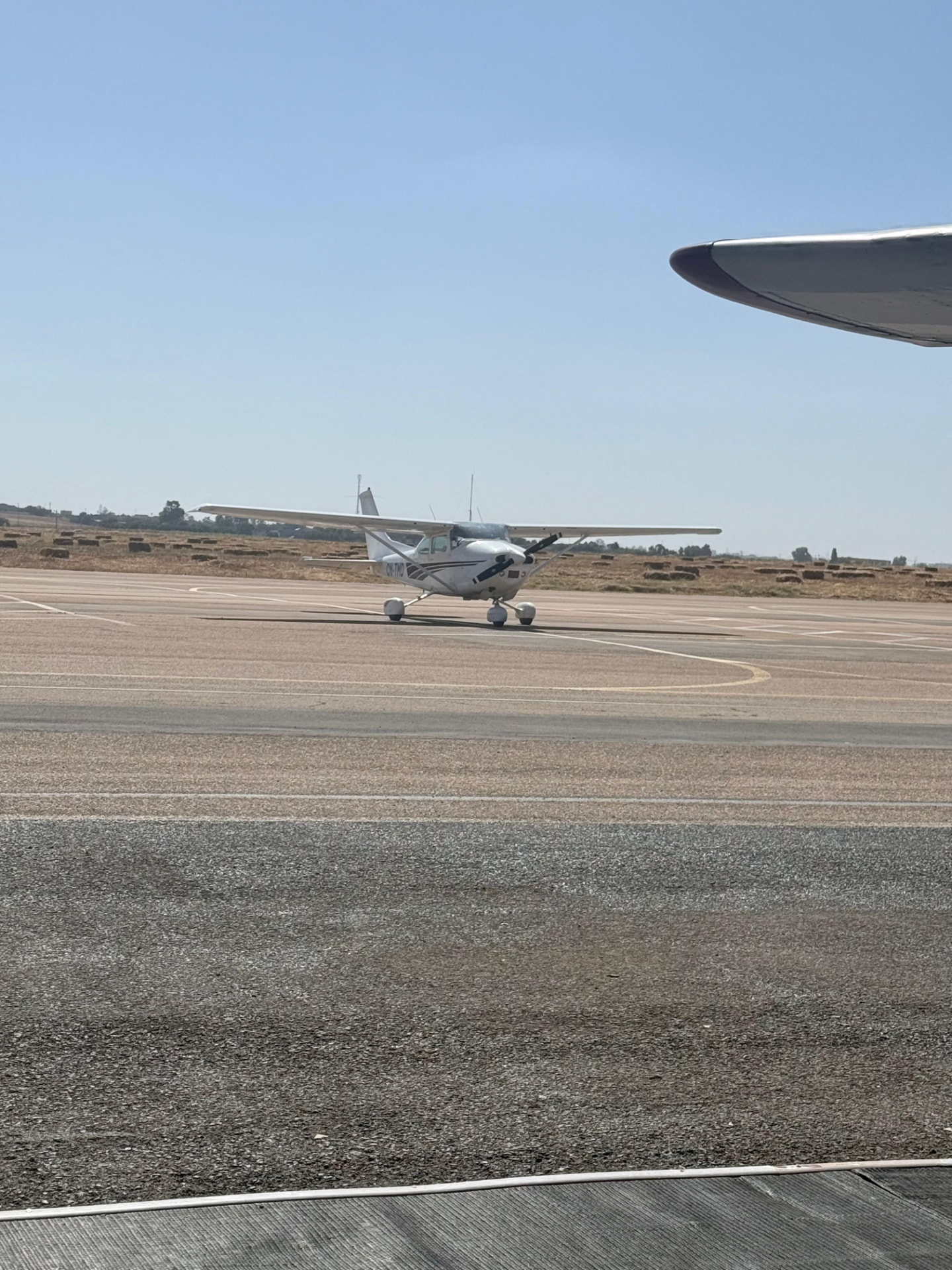 Un Cessna au roulage sur le tarmac, vu sous l'aile d'un autre avion
