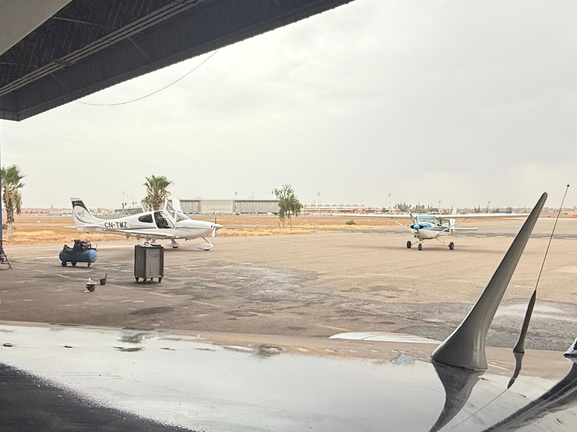Vue depuis le hangar sur l'aire de stationnement avec le CN-TMZ et un Cessna